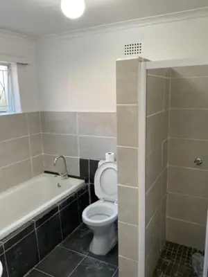a bathroom with a white toilet and a bath tub at Cub's Home in Cape Town