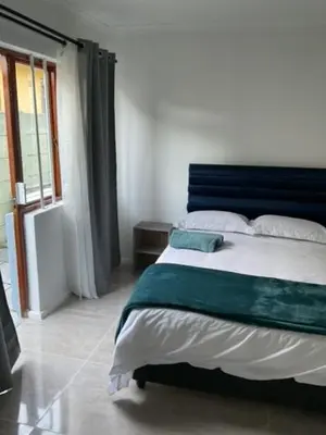 a bedroom with a large bed with a blue headboard at Cub's Home in Cape Town