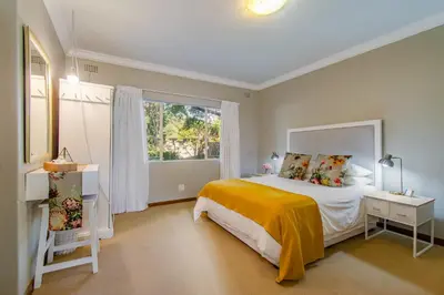 a bedroom with a bed and a large window at THE CORNER COTTAGE in Somerset West