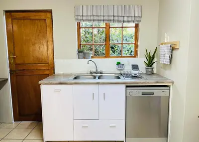 a white kitchen with a sink and a window at THE CORNER COTTAGE in Somerset West
