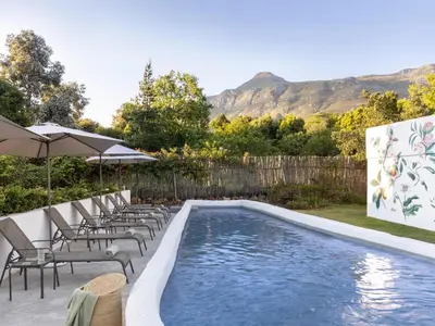 a swimming pool with lounge chairs and an umbrella at Greyton Lodge in Greyton