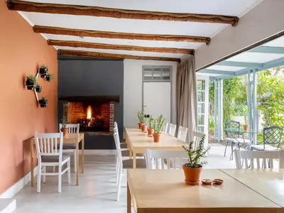 a dining room with tables and chairs and a fireplace at Greyton Lodge in Greyton