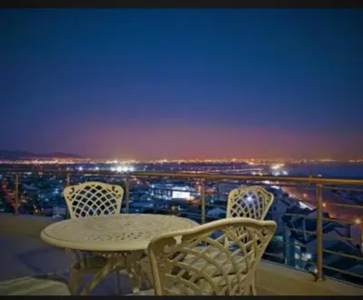 a table and chairs on a balcony at night at Blouberg,1106 Portico,Cape town in Cape Town