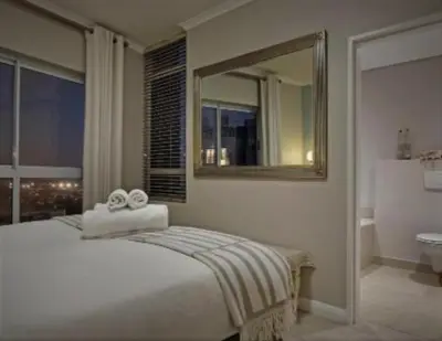a bedroom with a bed with a mirror and a bathroom at Blouberg,1106 Portico,Cape town in Cape Town