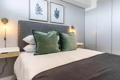 a bedroom with a large bed with green pillows at Burmeister403 - Modern 1 Bedroom Apartment across from Ocean in Cape Town