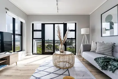 a living room with a couch and a table at Burmeister403 - Modern 1 Bedroom Apartment across from Ocean in Cape Town