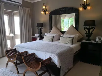 a bedroom with a large bed with two chairs at Perle Du Cap in Paarl