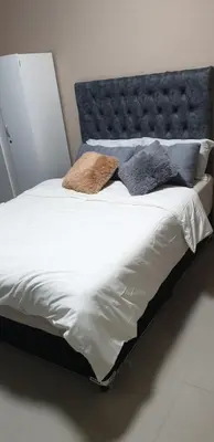 a bed with a blue headboard and pillows on it at PEACE LODGE in Cape Town