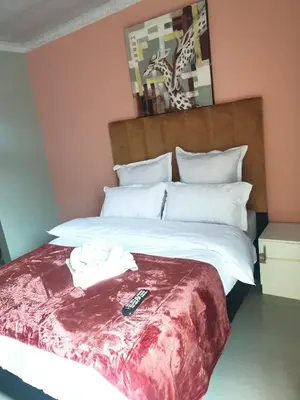 a bedroom with a bed with a remote control on it at PEACE LODGE in Cape Town