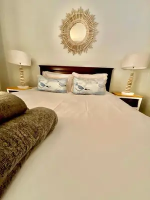 a bedroom with a large white bed with a mirror at 502 Portico in Cape Town