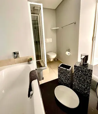 a bathroom with a toilet and a bath tub at 502 Portico in Cape Town