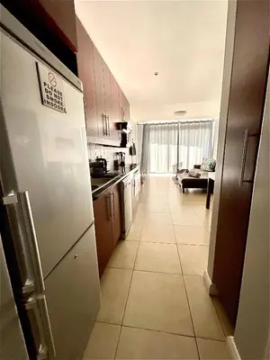 a kitchen with a white refrigerator and a living room at 502 Portico in Cape Town