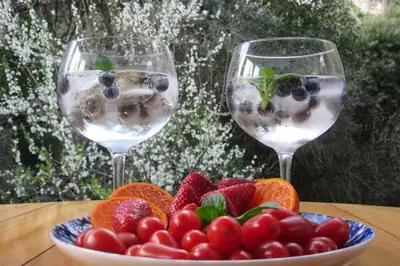 two glasses of water and a bowl of fruit on a table at Pecan Tree Forest Studio B in Stellenbosch