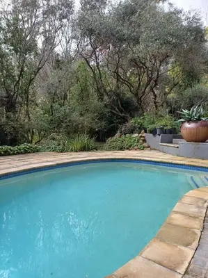 a large blue swimming pool with trees in the background at Pecan Tree Forest Studio B in Stellenbosch