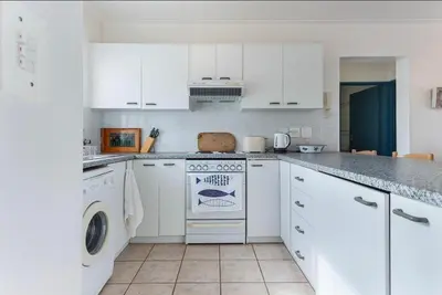 a kitchen with white cabinets and a washer and dryer at 30 Nagua Bay in Cape Town