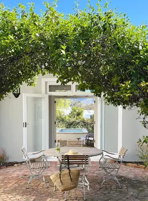 a patio with a table and chairs under a tree at La Belle Vie in Franschhoek
