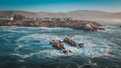 a group of people standing on rocks in the ocean at TnT on Main in Hermanus