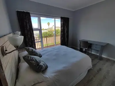 a bedroom with a bed with a window and a desk at Lovely 2 bedroom condo with balcony and a view! in Cape Town