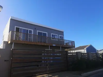 a house with a deck and a fence at Lovely 2 bedroom condo with balcony and a view! in Cape Town