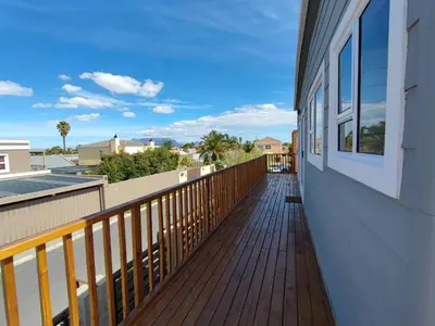 a balcony with a wooden deck with a view of the ocean at Lovely 2 bedroom condo with balcony and a view! in Cape Town