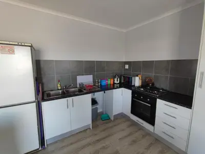 a kitchen with white cabinets and a black stove at Lovely 2 bedroom condo with balcony and a view! in Cape Town