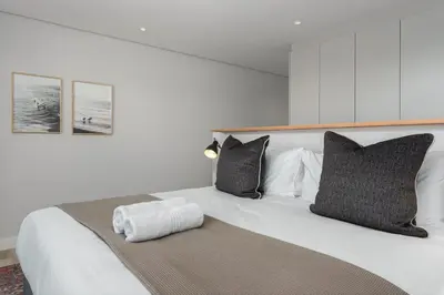 a large white bed with black and white pillows at Burmeister on Park Apartments in Cape Town
