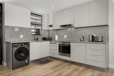 a kitchen with white cabinets and a washer at Burmeister on Park Apartments in Cape Town