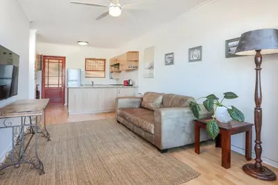 a living room with a couch and a kitchen at Oak on Main in Hermanus