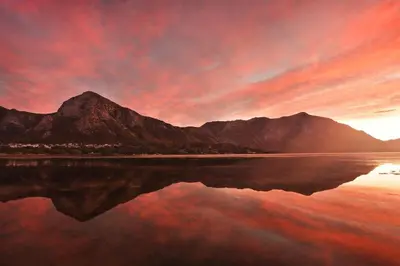 a sunset over a body of water with a mountain at Oak on Main in Hermanus