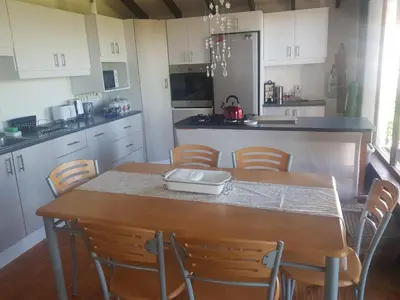 a kitchen with a wooden table with chairs and a counter at Relax on Blair in Cape Town