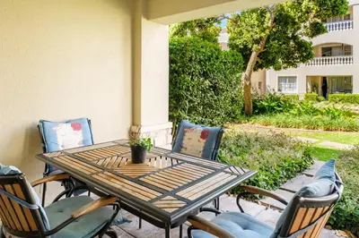 a wooden table and chairs on a patio at Belina - Bougain Villas Premier in Cape Town