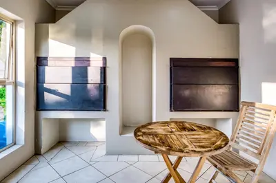 a rattan chair in a room with windows at Belina - Bougain Villas Premier in Cape Town