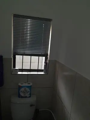 a bathroom with a window and a toilet with a tank at Oxford Getaway-House in Cape Town