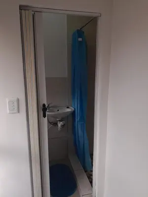 a shower with a sink and a blue shower curtain at Oxford Getaway-House in Cape Town