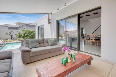 a living room with a couch and a table at Spacious Shared 3-Bedroom Villa Near Blouberg Beach Pool, Wi-Fi, Braai in Cape Town
