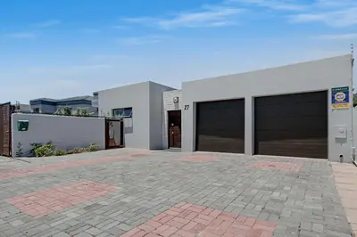 a white building with two garage doors on it at Spacious Shared 3-Bedroom Villa Near Blouberg Beach Pool, Wi-Fi, Braai in Cape Town