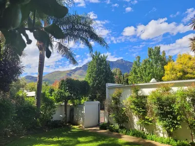 a house with a palm tree and mountains in the background at Stellenbosch Paradyskloof Unit in Stellenbosch