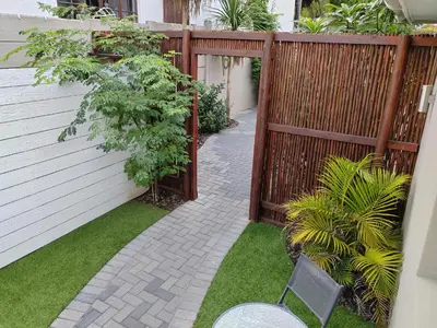 a garden with a wooden fence and a chair at Leafy Retreat Kenridge Trendy in Durbanville
