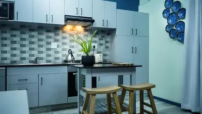 a kitchen with white cabinets and two stools at 1-bedroom apartment with secure basement parking in Stellenbosch
