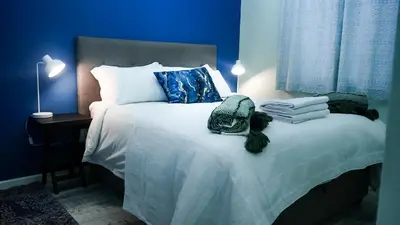 a blue bedroom with a large bed with blue walls at 1-bedroom apartment with secure basement parking in Stellenbosch