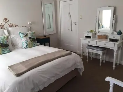 a bedroom with a bed and a desk and a mirror at Pat's Place in Hermanus