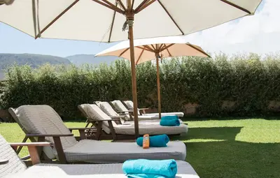 three lounge chairs with umbrellas on the grass at Pat's Place in Hermanus