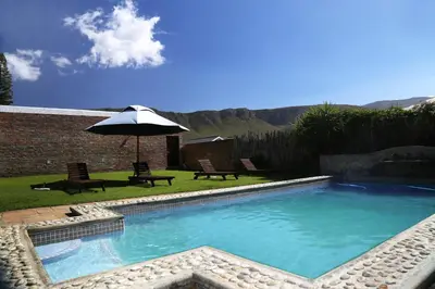 a swimming pool with two chairs and an umbrella at Pat's Place in Hermanus