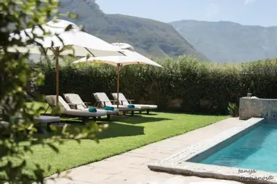 a group of chairs and an umbrella next to a pool at Pat's Place in Hermanus