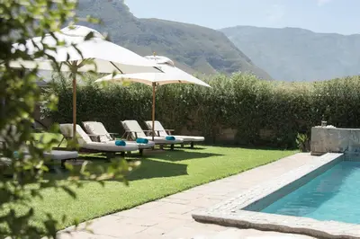 a pool with umbrellas and lounge chairs next to a pool at Pat's Place in Hermanus