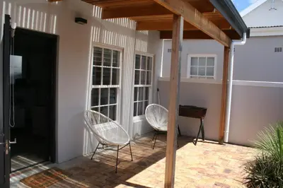 a patio with two chairs and a table at Botany House, in the heart of Hermanus in Hermanus