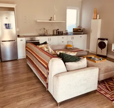 a living room with a couch and a kitchen at Botany House, in the heart of Hermanus in Hermanus