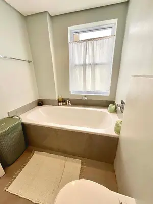 a bathroom with a tub and a window and a toilet at 706 Portico in Cape Town
