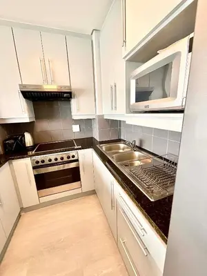a kitchen with white cabinets and a sink and a microwave at 706 Portico in Cape Town