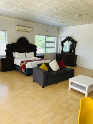 a bedroom with a bed and a couch and a table at African Haven Guest House in Cape Town
